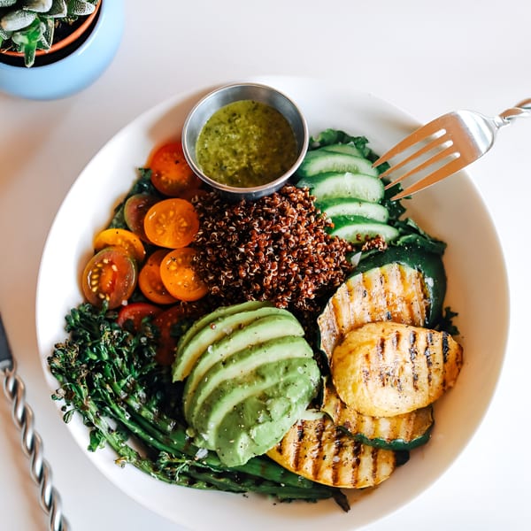 A vibrant Banyan Kitchen cafe bowl with quinoa, grilled zucchini, avocado, tomatoes, and greens.