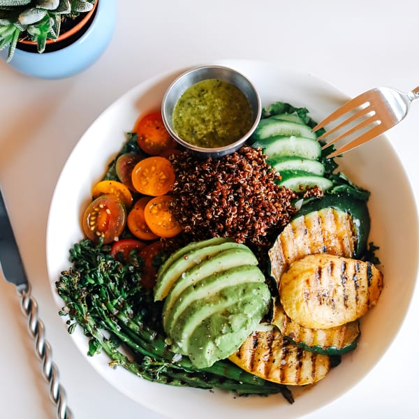 A colorful Banyan Kitchen cafe bowl with quinoa, grilled vegetables, avocado, and cherry tomatoes.