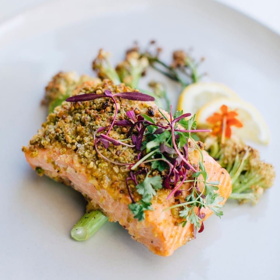 Banyan Kitchen's salmon with a herb crust, microgreens, roasted broccoli, and lemon slices.