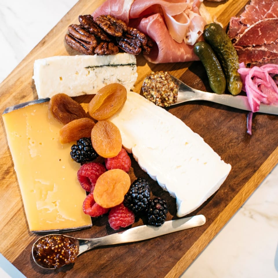 A Banyan Kitchen charcuterie board with cheeses, cured meats, fruits, nuts, pickles, and fig jam.