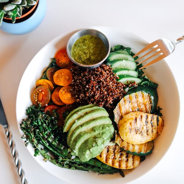 A vibrant Banyan Kitchen cafe bowl with grilled vegetables, quinoa, avocado, and cherry tomatoes.