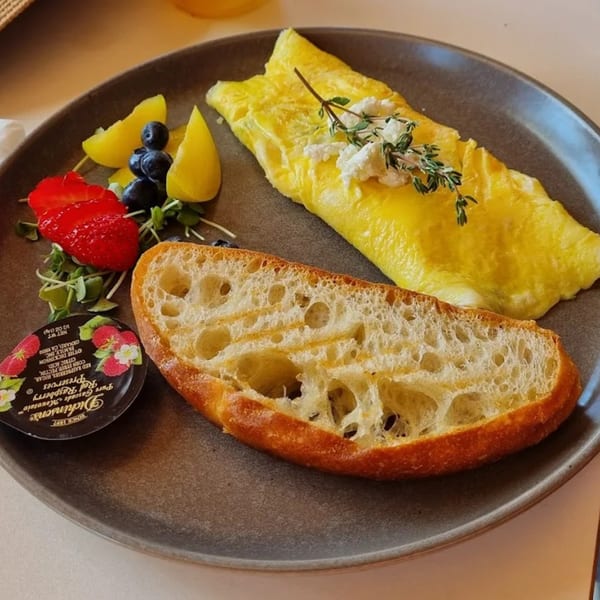 A Banyan Kitchen breakfast plate with an omelet, fruit, bread, and raspberry preserves.